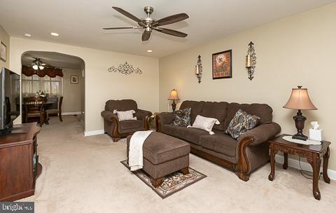 carpeted living room with ceiling fan