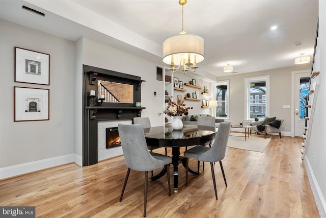 dining area with light hardwood / wood-style flooring and a notable chandelier