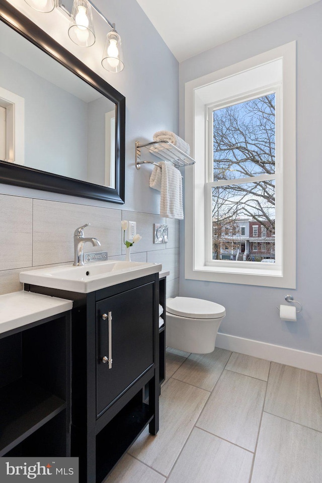 bathroom with vanity, toilet, and tile walls