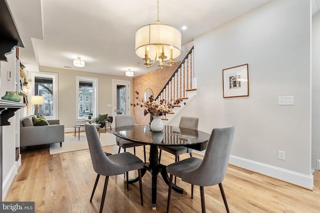 dining space with a chandelier, light wood finished floors, stairway, and baseboards