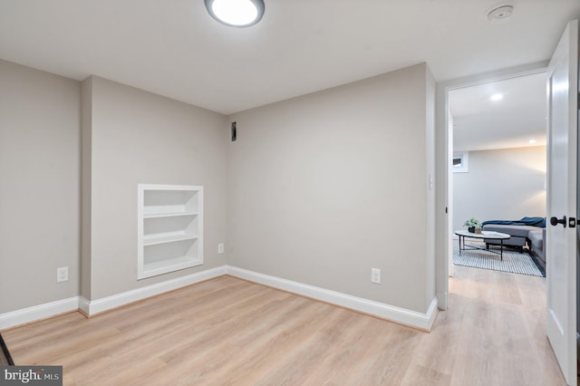 unfurnished room featuring built in features and light wood-type flooring