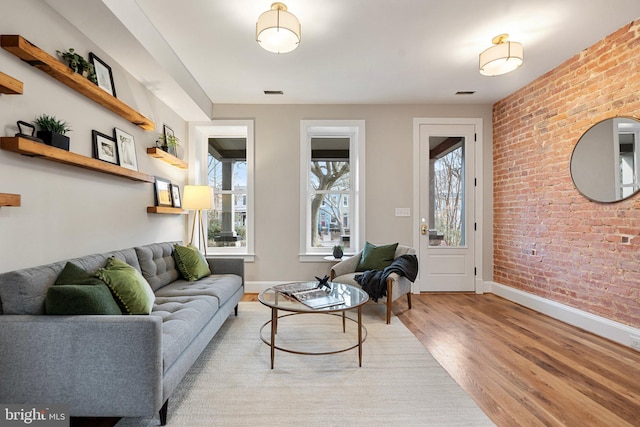 living room featuring brick wall and light hardwood / wood-style flooring