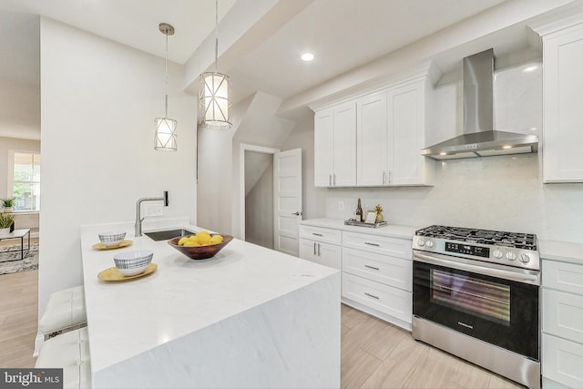 kitchen with white cabinets, gas range, and wall chimney exhaust hood