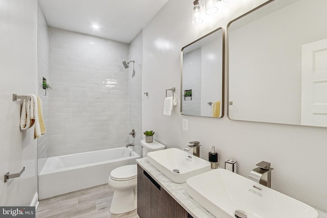 full bathroom with vanity, tiled shower / bath combo, toilet, and hardwood / wood-style flooring