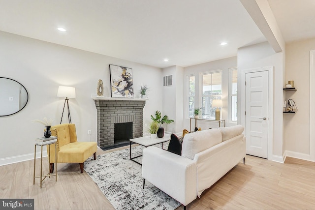 living room featuring a brick fireplace and light hardwood / wood-style flooring