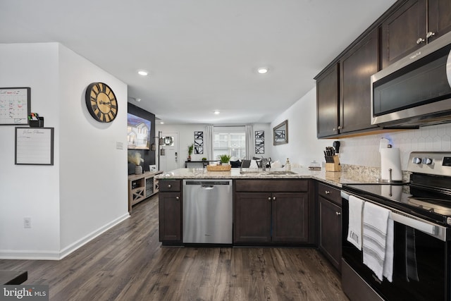 kitchen featuring light stone counters, appliances with stainless steel finishes, kitchen peninsula, and sink