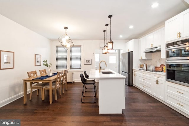 kitchen featuring sink, a breakfast bar area, hanging light fixtures, a center island with sink, and stainless steel appliances