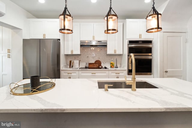 kitchen featuring stainless steel appliances, a kitchen island with sink, hanging light fixtures, and white cabinets