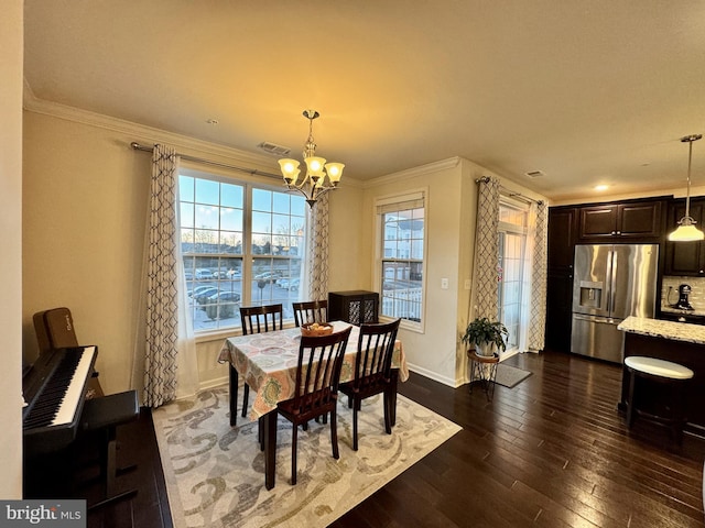 dining room with dark wood-type flooring, crown molding, and an inviting chandelier