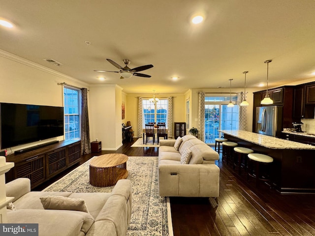 living room featuring crown molding, dark hardwood / wood-style flooring, and ceiling fan with notable chandelier