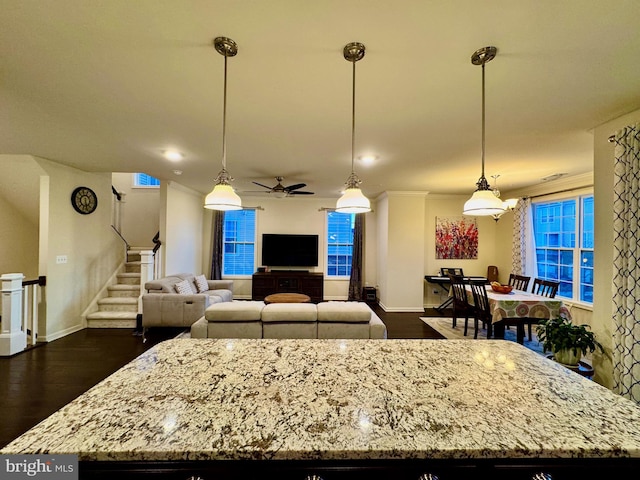 kitchen with dark wood-type flooring, ornamental molding, decorative light fixtures, and a center island