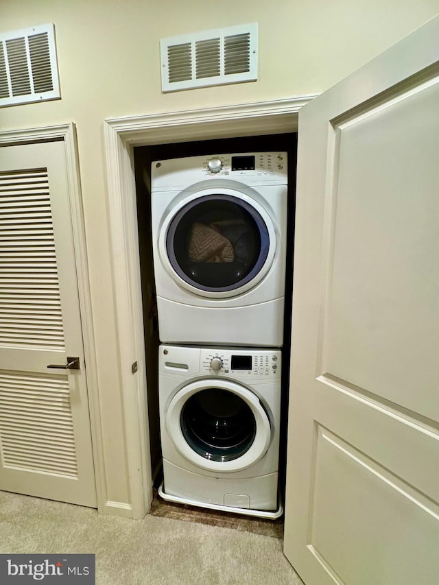 laundry area with stacked washer / dryer and light colored carpet