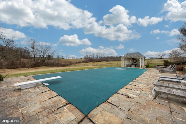 view of pool with a diving board, a yard, an outbuilding, and a patio area