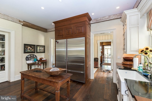 kitchen featuring dark hardwood / wood-style flooring, sink, built in fridge, and white cabinets