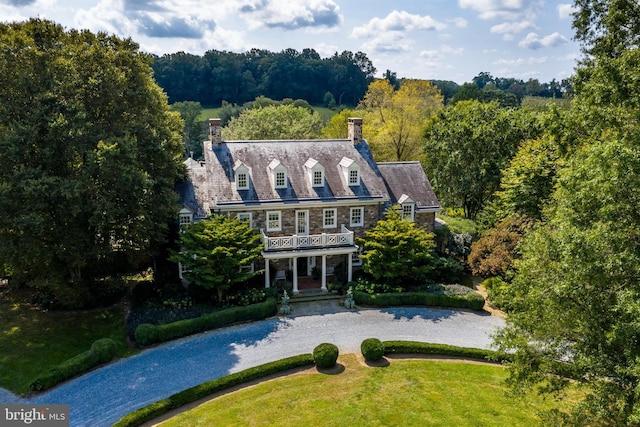 rear view of property featuring a balcony and a yard