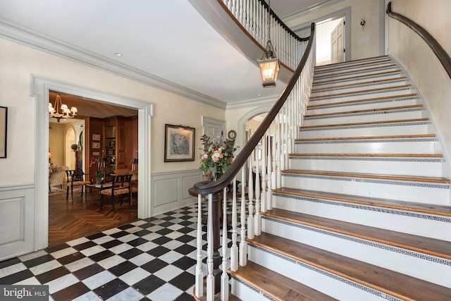 staircase featuring crown molding and a chandelier