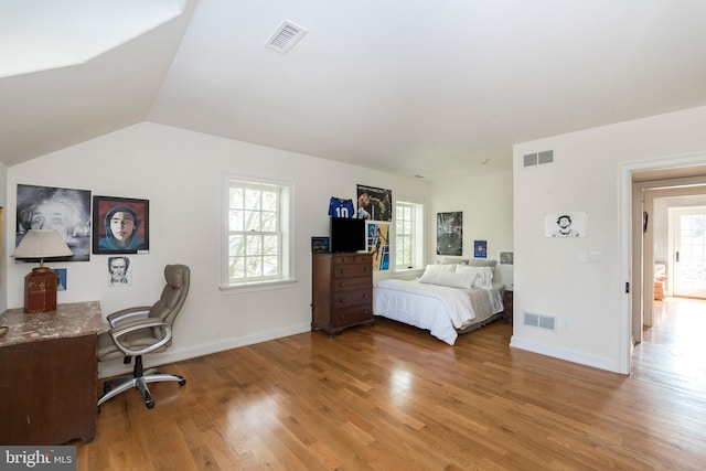 bedroom with hardwood / wood-style flooring, vaulted ceiling, and multiple windows