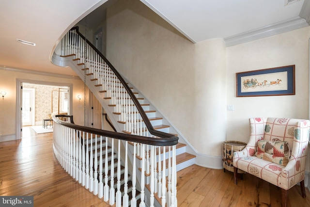 staircase featuring ornamental molding and wood-type flooring