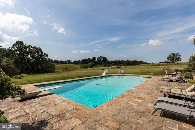 view of pool with a diving board, a patio, and a lawn