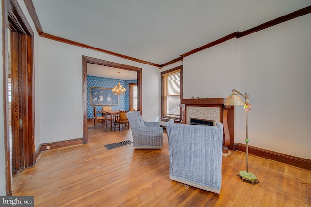 living area with baseboards, wood finished floors, visible vents, and crown molding