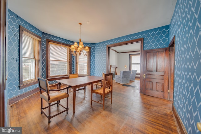 dining area with wallpapered walls, visible vents, baseboards, wood finished floors, and an inviting chandelier