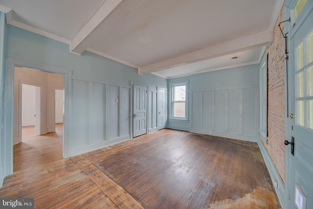 interior space featuring a decorative wall, beamed ceiling, and wood finished floors