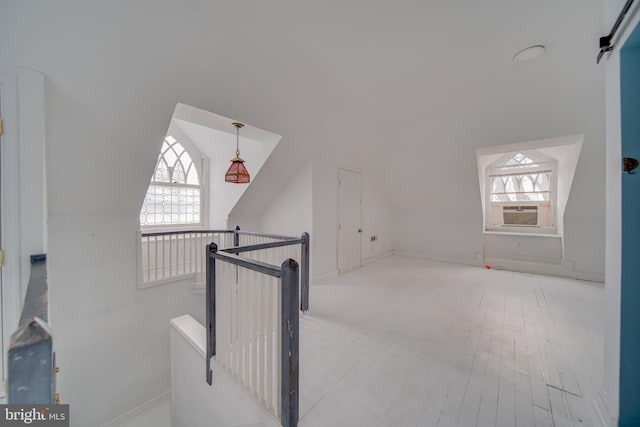 additional living space with vaulted ceiling, a wealth of natural light, light hardwood / wood-style floors, and cooling unit