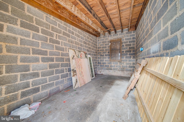 interior space with concrete block wall and unfinished concrete flooring