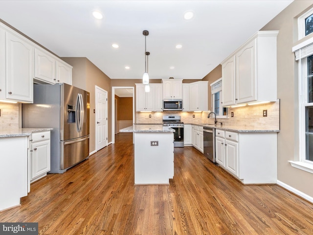 kitchen featuring white cabinetry, decorative light fixtures, a kitchen island, and appliances with stainless steel finishes