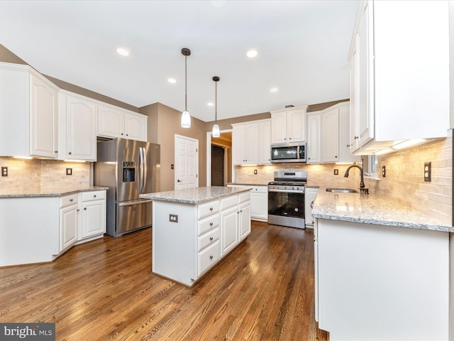 kitchen featuring stainless steel appliances, decorative light fixtures, a center island, and white cabinets