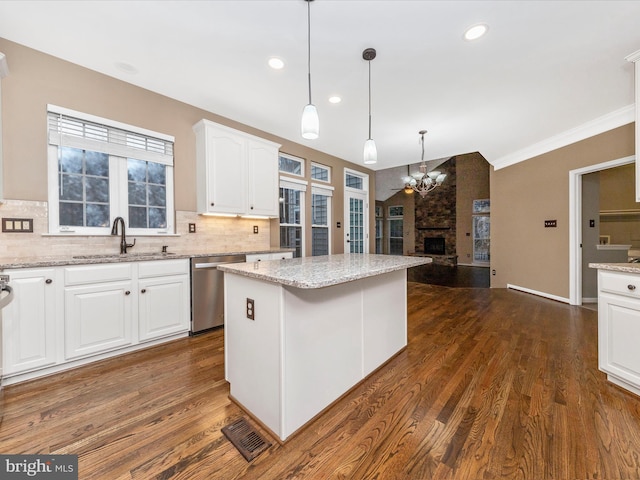 kitchen with pendant lighting, sink, dishwasher, white cabinetry, and a kitchen island