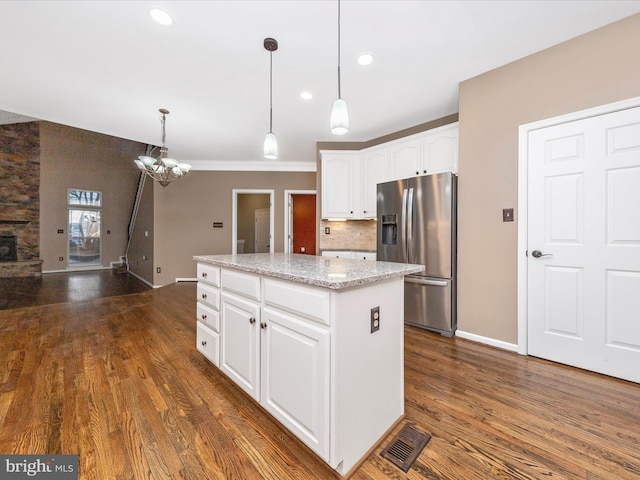 kitchen with white cabinetry, stainless steel refrigerator with ice dispenser, light stone counters, a kitchen island, and decorative light fixtures