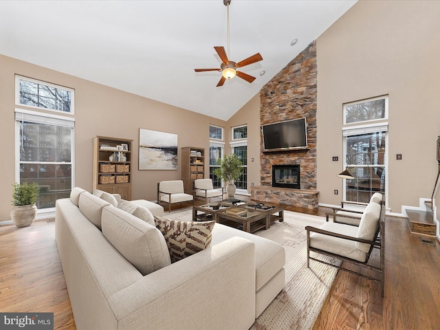 living room featuring ceiling fan, high vaulted ceiling, a fireplace, and light hardwood / wood-style floors