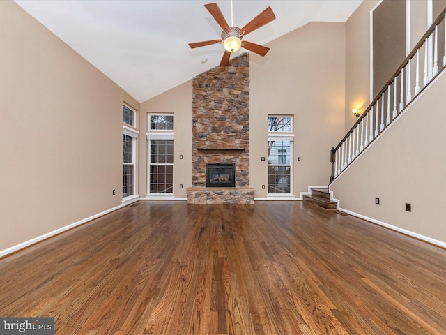 unfurnished living room featuring a stone fireplace, high vaulted ceiling, dark hardwood / wood-style floors, and ceiling fan