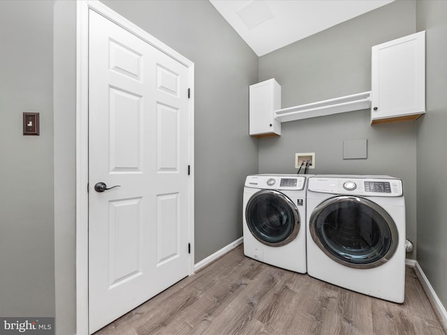 laundry area featuring independent washer and dryer, light hardwood / wood-style flooring, and cabinets