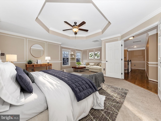 carpeted bedroom with ceiling fan, ornamental molding, and a raised ceiling