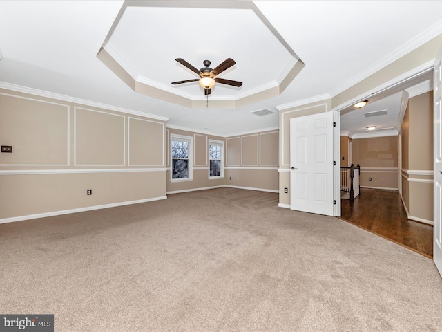 unfurnished living room with crown molding, a raised ceiling, and carpet floors