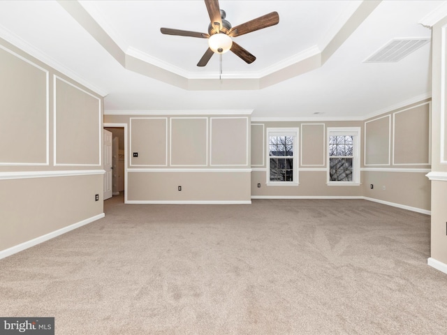 unfurnished living room with crown molding, light colored carpet, a tray ceiling, and ceiling fan