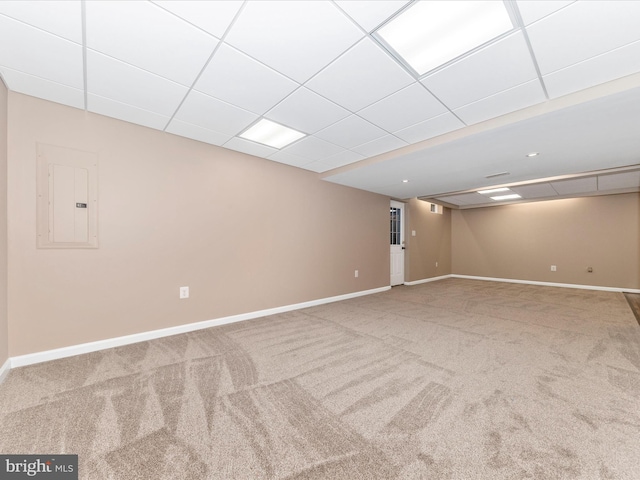 basement featuring carpet, a drop ceiling, and electric panel