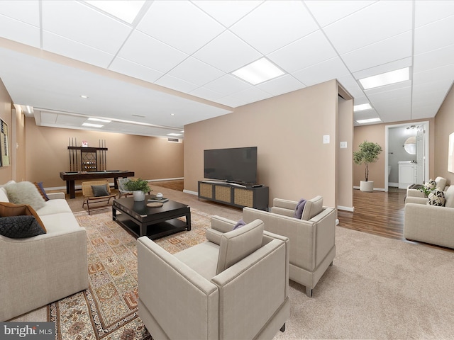 living room featuring light hardwood / wood-style flooring and a drop ceiling