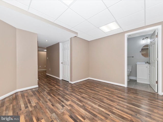 spare room featuring sink, dark wood-type flooring, and a paneled ceiling