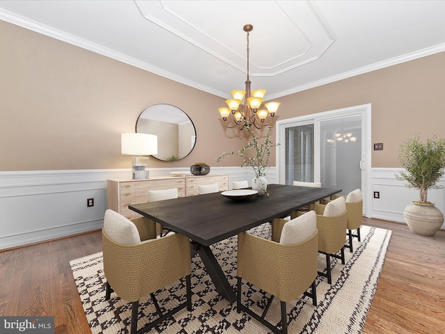 dining space with ornamental molding, a chandelier, and hardwood / wood-style floors