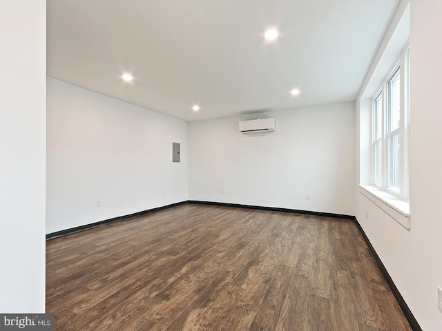 spare room with dark wood-type flooring, a wall unit AC, and electric panel