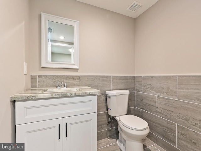 bathroom with vanity, tile walls, tile patterned floors, and toilet