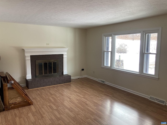 unfurnished living room featuring hardwood / wood-style floors, a fireplace, and a textured ceiling