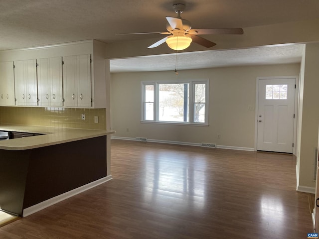 kitchen featuring wood-type flooring, a textured ceiling, white cabinets, ceiling fan, and backsplash