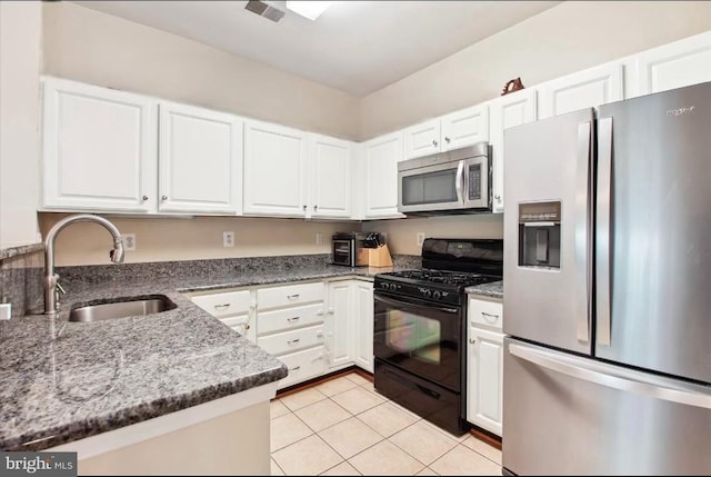 kitchen featuring sink, white cabinetry, dark stone counters, light tile patterned floors, and stainless steel appliances