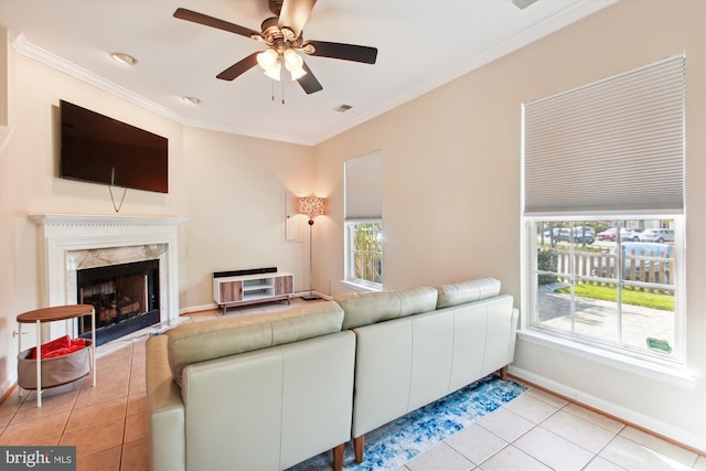 living room featuring light tile patterned floors, a high end fireplace, ornamental molding, and ceiling fan