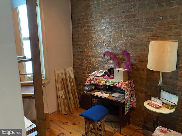 dining area with hardwood / wood-style flooring and brick wall