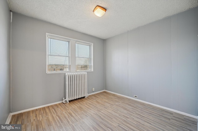 empty room featuring radiator, a textured ceiling, and light wood-type flooring